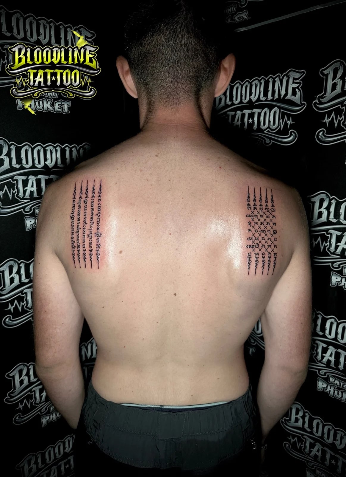 Traditional black ink Hah Taew (Five Lines) and Chat Petch (Diamond Armour) Sak Yant tattoos symmetrically placed on a man's upper back at Bloodline Tattoo Phuket.