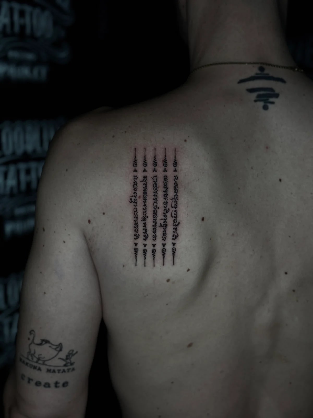 Hah Taew (Five Lines) Sak Yant with five vertical Khom script rows and unalome caps on the left shoulder blade at Bloodline Tattoo Phuket.