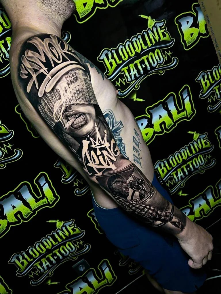 Detailed black and grey Chicano upper arm sleeve tattoo with a blindfolded smoking woman, graffiti script, masked gunman, and checkerboard detail at Bloodline Tattoo Bali.