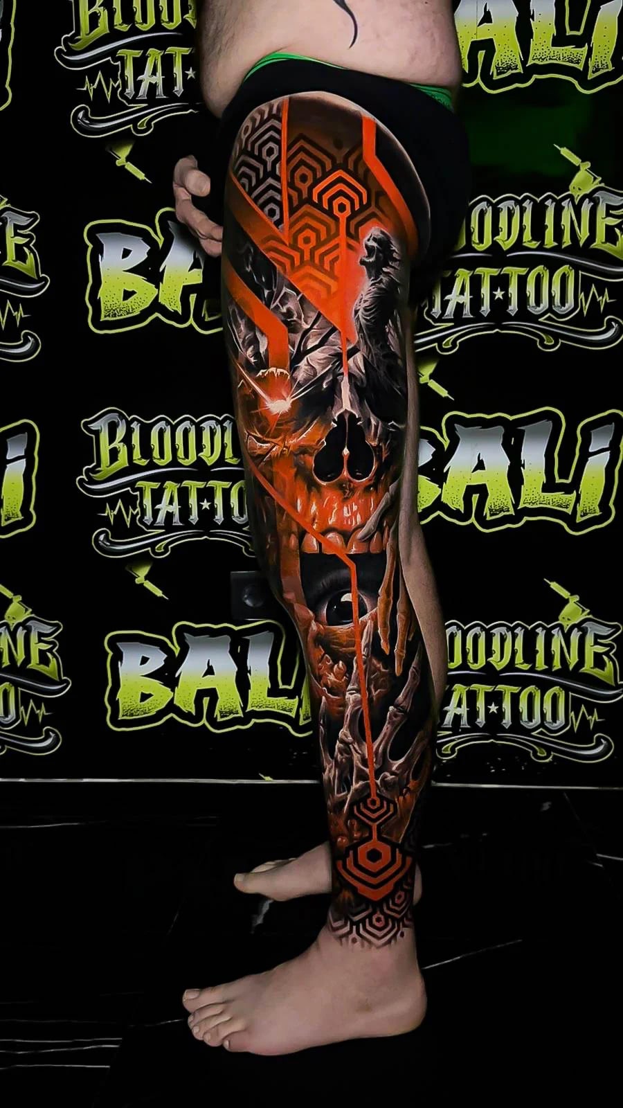 Colour dark fantasy leg sleeve tattoo with a skull, raven silhouette, geometric patterns, and glowing orange fracture lines at Bloodline Tattoo Bali.