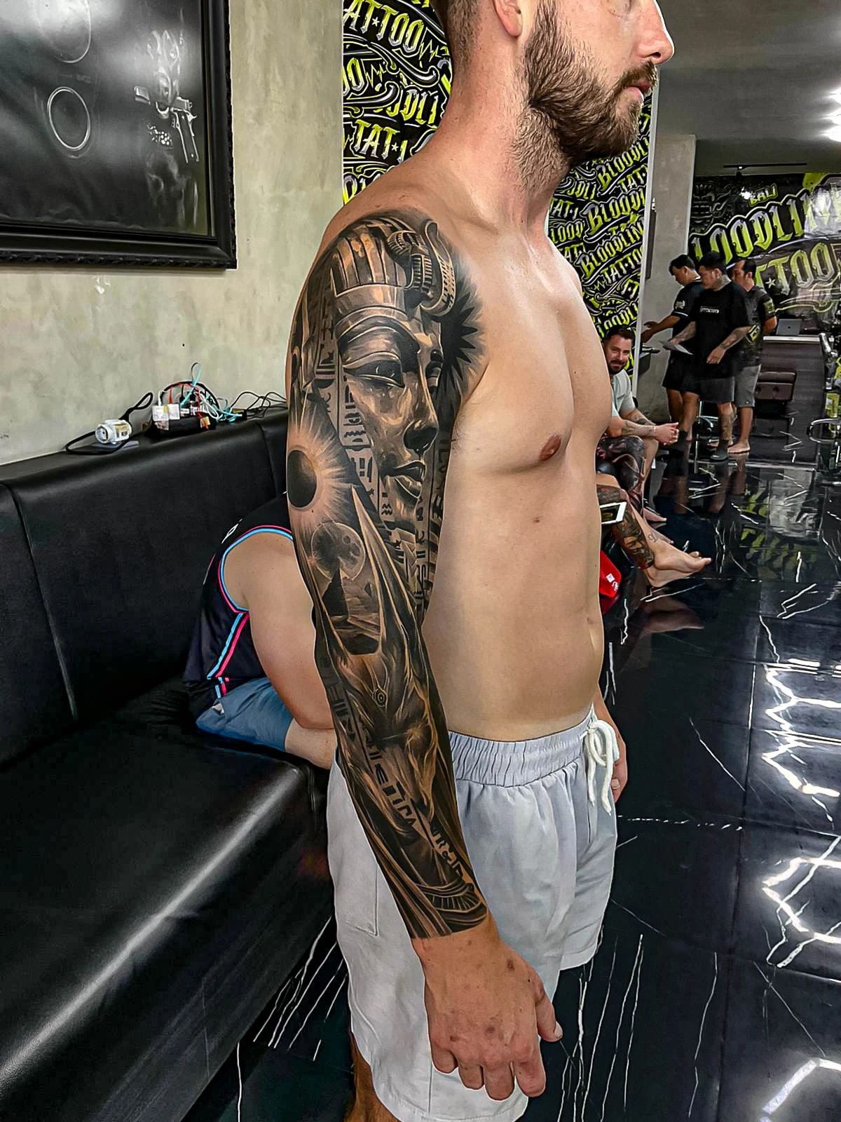Healed black-and-grey sleeve with an Egyptian queen, eclipse motifs, and geometric framing, showing smooth shading and crisp healed line integrity at Bloodline Tattoo Bali.